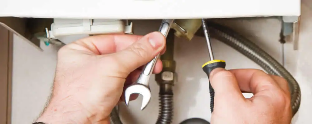 Boiler repair technician tightening pipe fittings and connections in Green Bay, WI