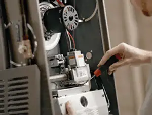 Furnace repair technician inspecting internal components and wiring in Green Bay, WI