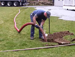 Septic pumping technician servicing a residential septic tank with a vacuum hose in Green Bay, WI