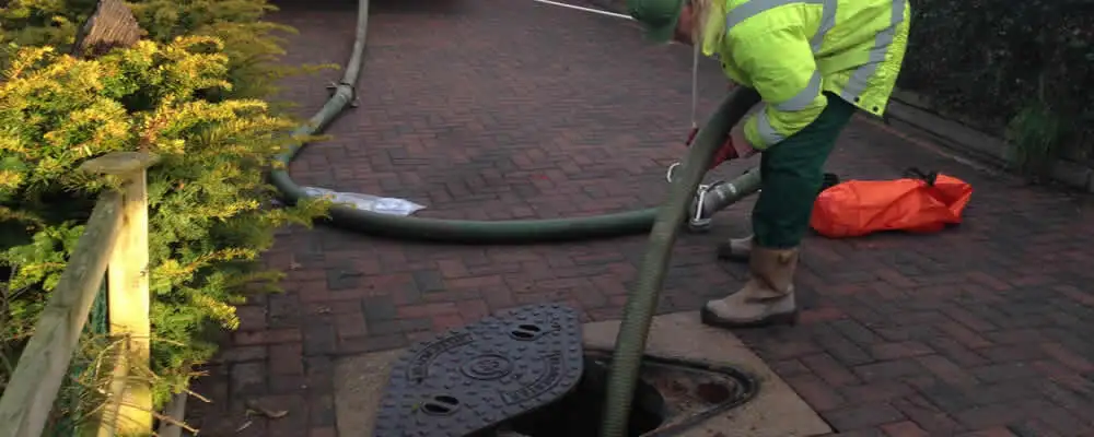 Septic tank cleaning technician servicing a septic tank with a vacuum hose in Green Bay, WI