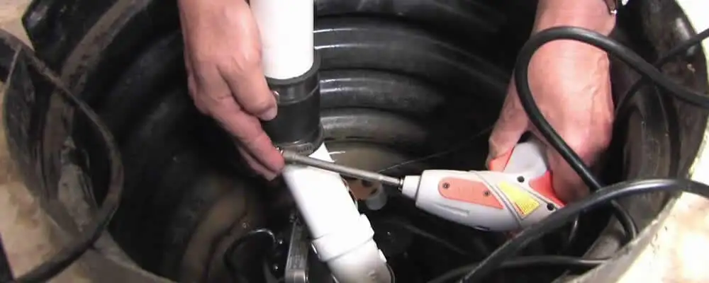 Sump pump installation technician connecting PVC discharge piping in Green Bay, WI