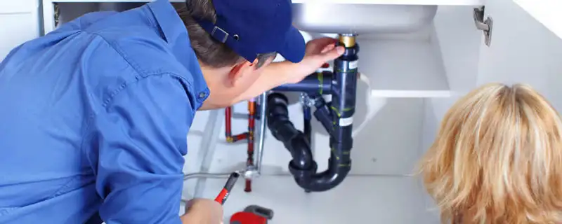 Plumber repairing under-sink drain pipes and fittings in Green Bay, WI